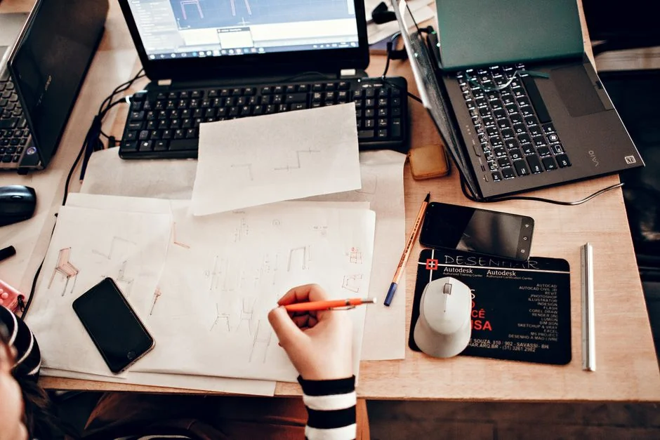 Un espace de travail moderne avec deux écrans d’ordinateur affichant des projets de conception web, mettant en avant la technologie et la productivité.